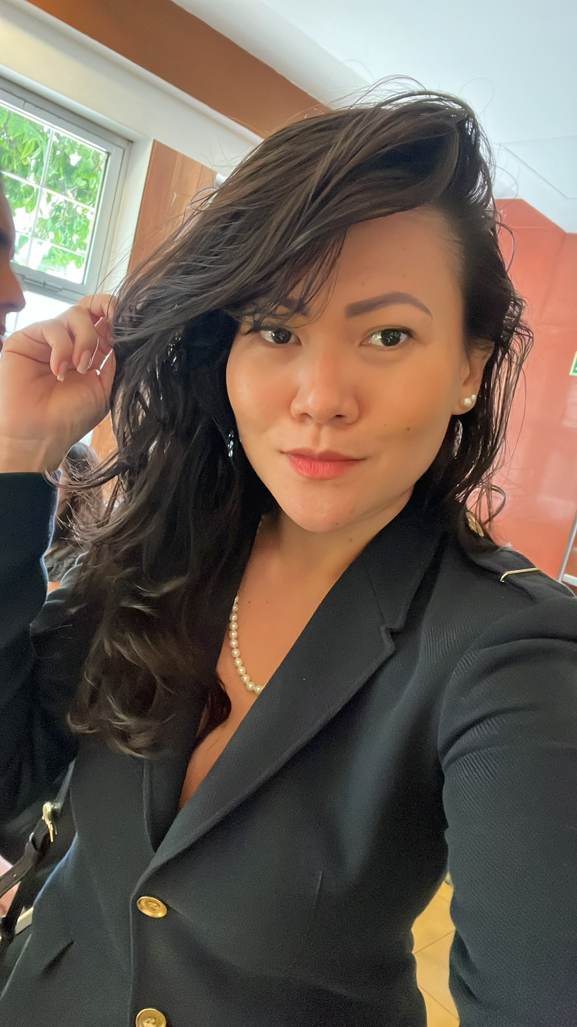 Retrato de Sílvia Yoshinaga usando blazer preto e colar de pérolas